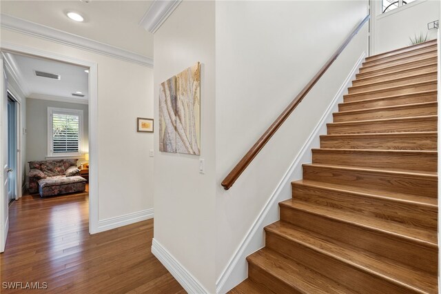 stairs featuring hardwood / wood-style floors and ornamental molding