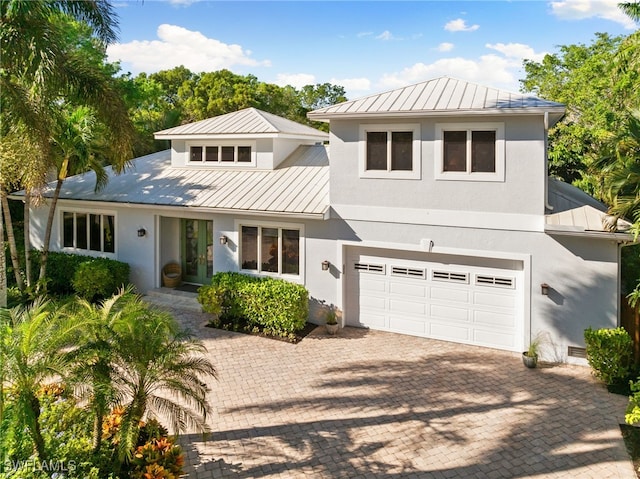 view of front of house with a garage, metal roof, a standing seam roof, decorative driveway, and stucco siding