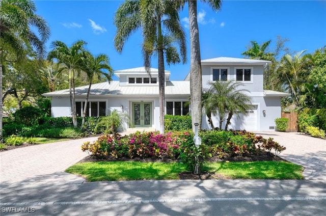 view of front of house featuring french doors, metal roof, an attached garage, stucco siding, and decorative driveway