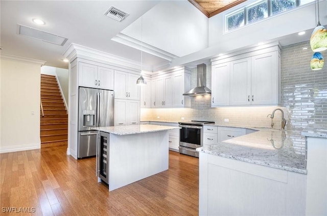 kitchen featuring stainless steel appliances, visible vents, ornamental molding, a sink, and wall chimney exhaust hood