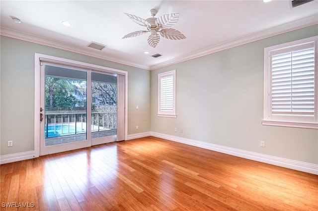 unfurnished room featuring light wood-style floors, ceiling fan, baseboards, ornamental molding, and visible vents
