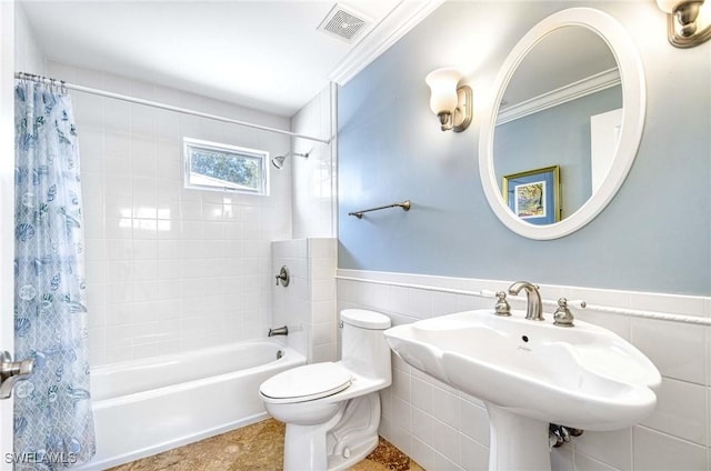 bathroom featuring shower / bath combo, a sink, a wainscoted wall, toilet, and visible vents