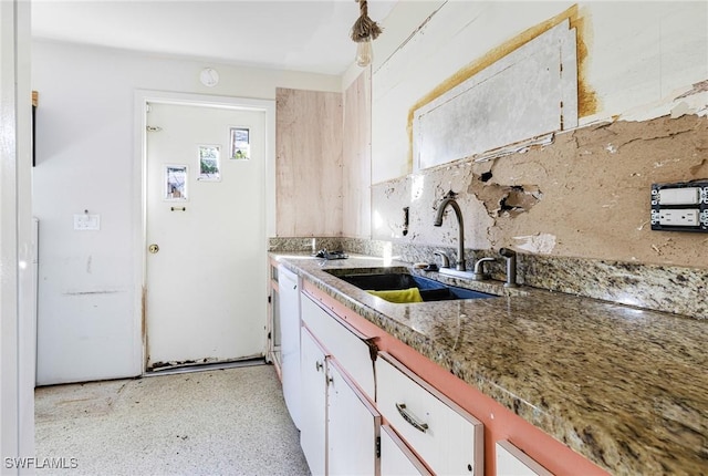 kitchen featuring white cabinets, dark stone countertops, and sink