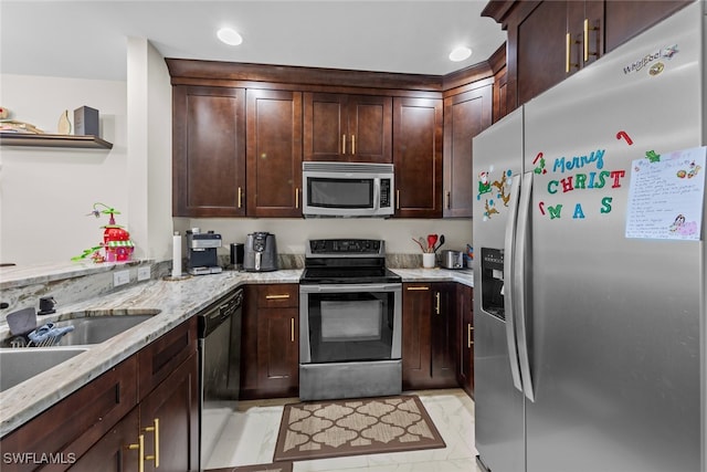 kitchen with light stone countertops, dark brown cabinetry, stainless steel appliances, and sink