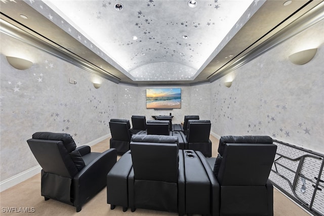 home theater room with a raised ceiling, light colored carpet, and ornamental molding