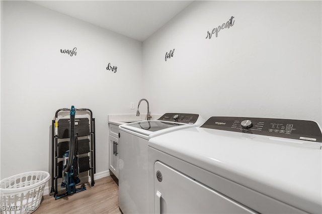 laundry area featuring cabinets, separate washer and dryer, sink, and light hardwood / wood-style flooring