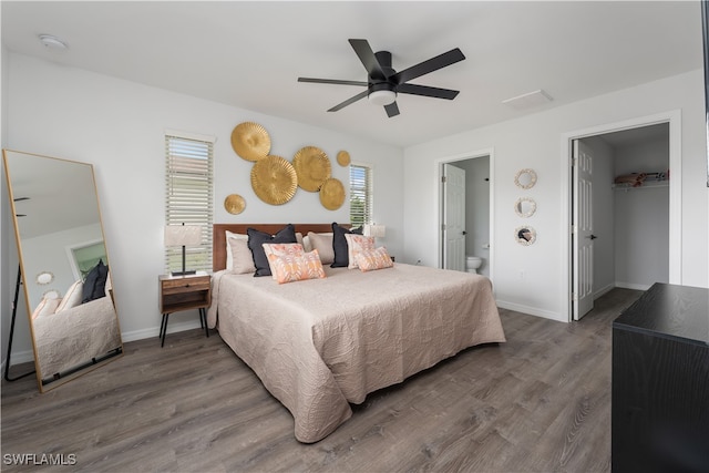 bedroom with multiple windows, ceiling fan, wood-type flooring, and a spacious closet