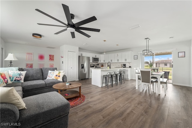 living room with ceiling fan with notable chandelier, wood-type flooring, and sink