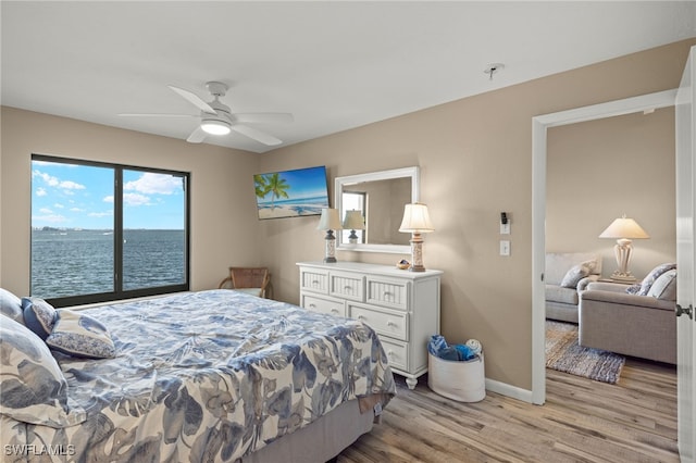 bedroom with ceiling fan, a water view, and light hardwood / wood-style flooring