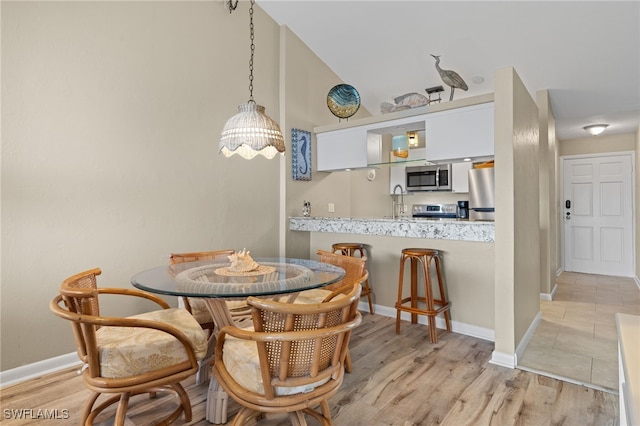 dining area featuring light wood-type flooring and vaulted ceiling