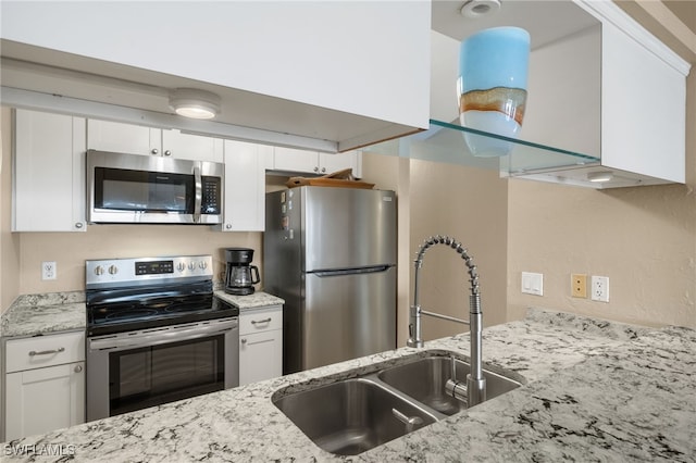 kitchen featuring appliances with stainless steel finishes, sink, white cabinetry, and light stone counters