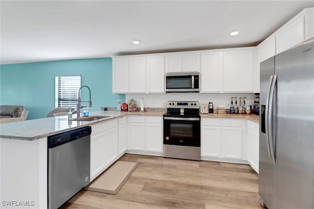 kitchen featuring kitchen peninsula, sink, stainless steel appliances, and light wood-type flooring