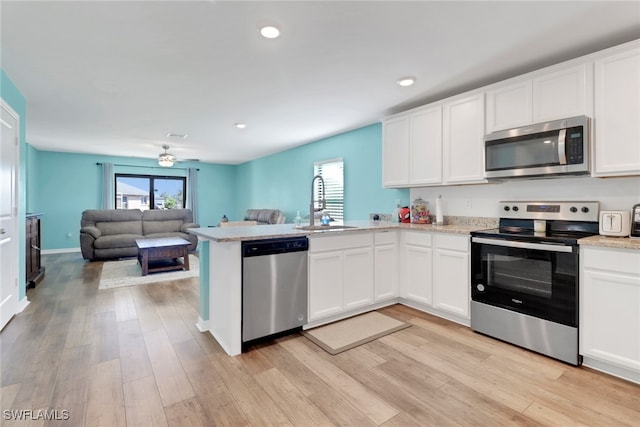 kitchen featuring white cabinetry, sink, stainless steel appliances, kitchen peninsula, and light wood-type flooring