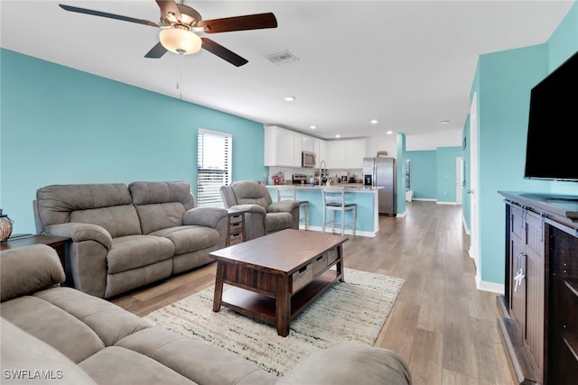 living room with ceiling fan and light hardwood / wood-style flooring