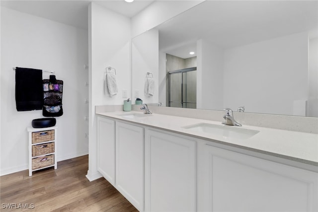 bathroom with hardwood / wood-style floors, vanity, and a shower with shower door