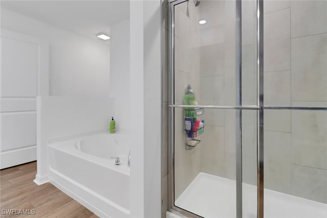 bathroom with hardwood / wood-style flooring and independent shower and bath