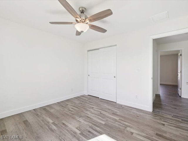 unfurnished bedroom with ceiling fan, a closet, and wood-type flooring