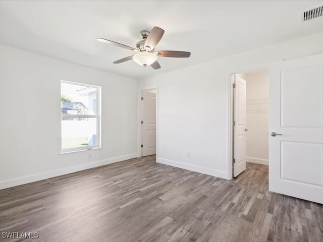 unfurnished bedroom with light hardwood / wood-style flooring, a spacious closet, a closet, and ceiling fan