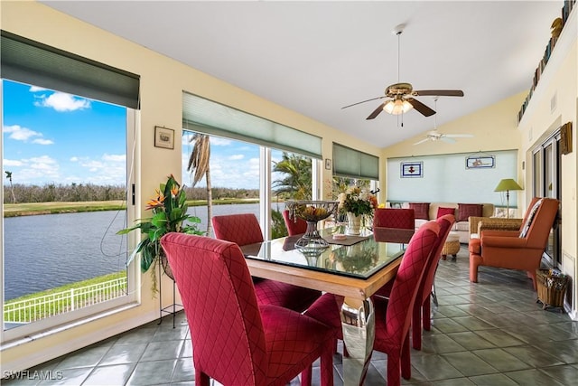 dining space with lofted ceiling, dark tile patterned floors, ceiling fan, and a water view