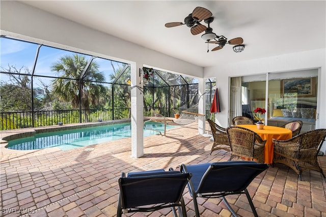 view of pool featuring glass enclosure, ceiling fan, and a patio area