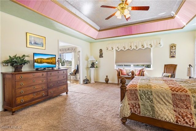 carpeted bedroom featuring a raised ceiling, ceiling fan, and ornamental molding