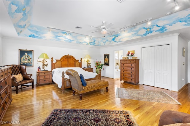 bedroom featuring crown molding, rail lighting, hardwood / wood-style flooring, ceiling fan, and a closet