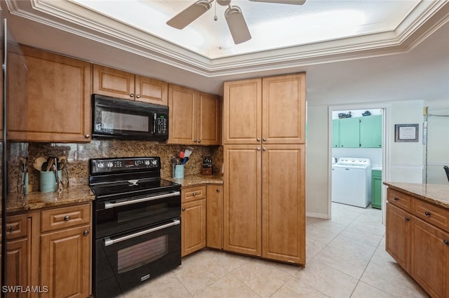 kitchen with black appliances, light stone counters, ornamental molding, and a tray ceiling