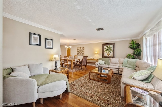 living room with a notable chandelier, wood-type flooring, a textured ceiling, and ornamental molding