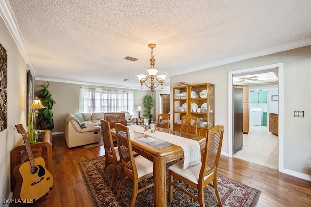 dining area with hardwood / wood-style flooring, crown molding, washer / clothes dryer, and a textured ceiling