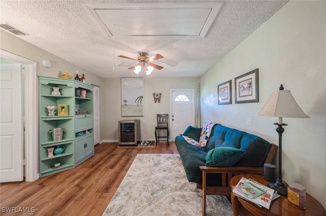 living room featuring a textured ceiling, dark hardwood / wood-style floors, wine cooler, and ceiling fan