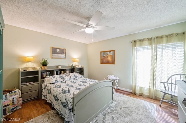 bedroom featuring ceiling fan, wood-type flooring, and a textured ceiling