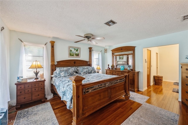 bedroom with a textured ceiling, hardwood / wood-style flooring, and ceiling fan