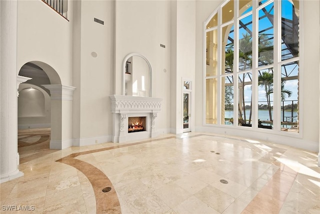 28790 Blaisdell Dr, Naples, FL 34119 - unfurnished living room with a towering ceiling, healthy amount of natural light, arched walkways, a premium fireplace, and baseboards