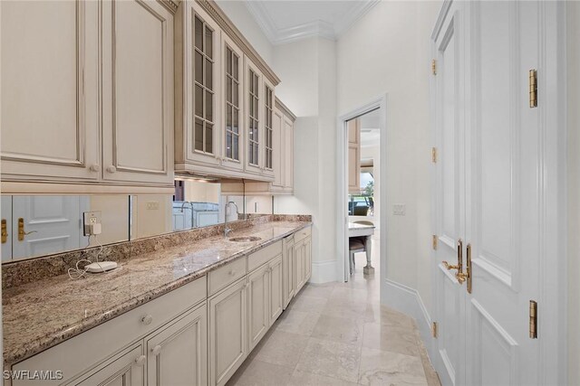 28790 Blaisdell Dr, Naples, FL 34119 - kitchen featuring cream cabinets, crown molding, glass insert cabinets, baseboards, and light stone countertops