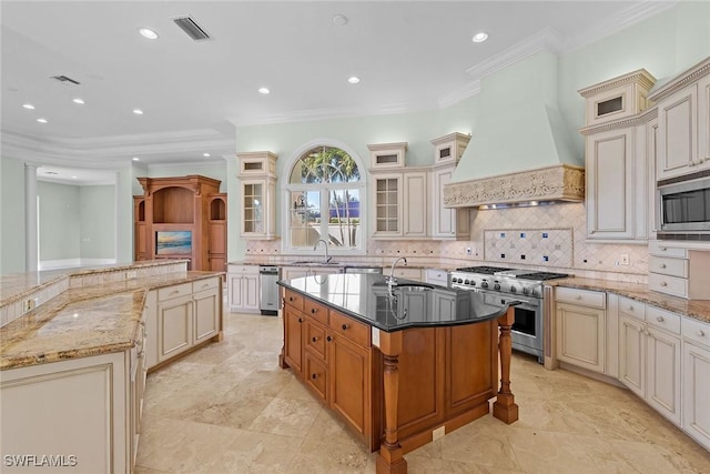 28790 Blaisdell Dr, Naples, FL 34119 - kitchen featuring appliances with stainless steel finishes, a center island with sink, cream cabinets, decorative backsplash, and crown molding