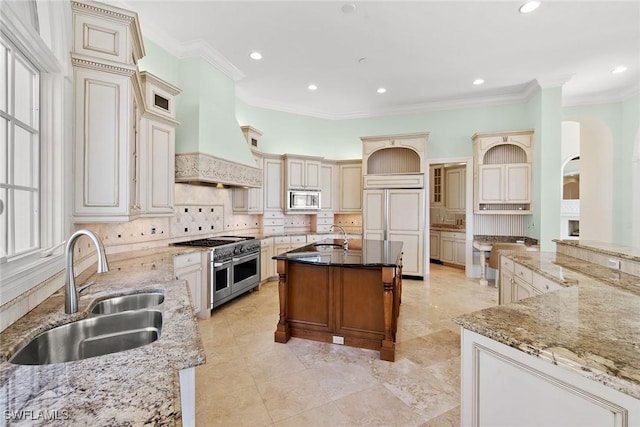 28790 Blaisdell Dr, Naples, FL 34119 - kitchen featuring built in appliances, a sink, cream cabinetry, premium range hood, and a spacious island