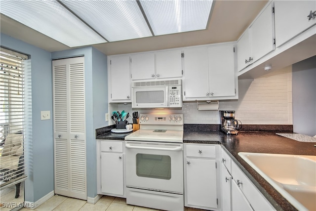 kitchen with sink, tasteful backsplash, light tile patterned flooring, white appliances, and white cabinets