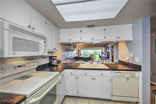 kitchen with white cabinets, white appliances, sink, and a skylight