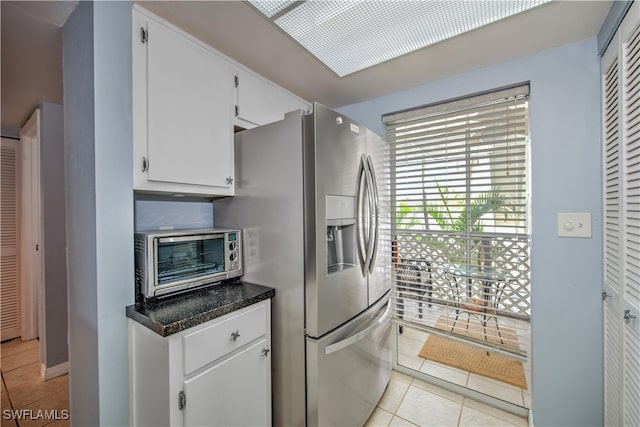 kitchen with white cabinets, stainless steel refrigerator with ice dispenser, and light tile patterned floors