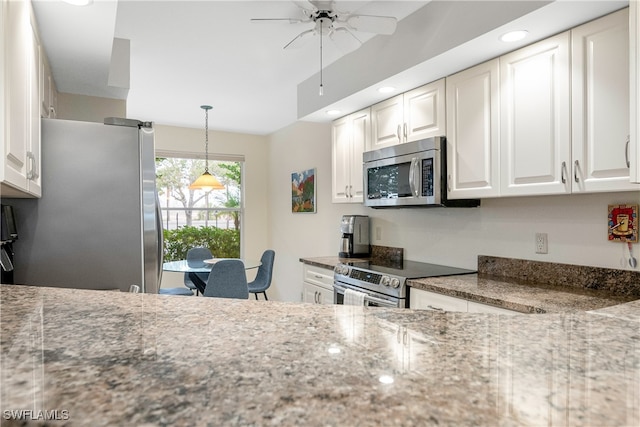 kitchen with stainless steel appliances, ceiling fan, stone countertops, white cabinetry, and hanging light fixtures