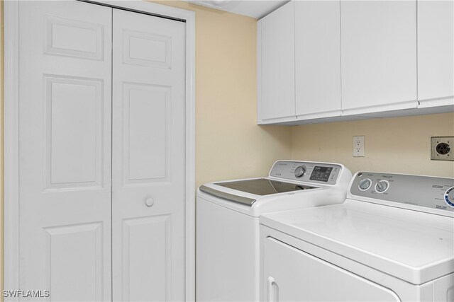 clothes washing area featuring cabinets and washing machine and clothes dryer