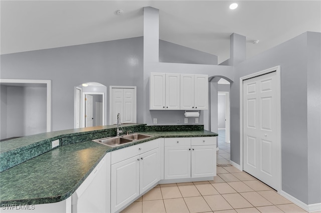 kitchen featuring high vaulted ceiling, white dishwasher, sink, light tile patterned floors, and white cabinetry