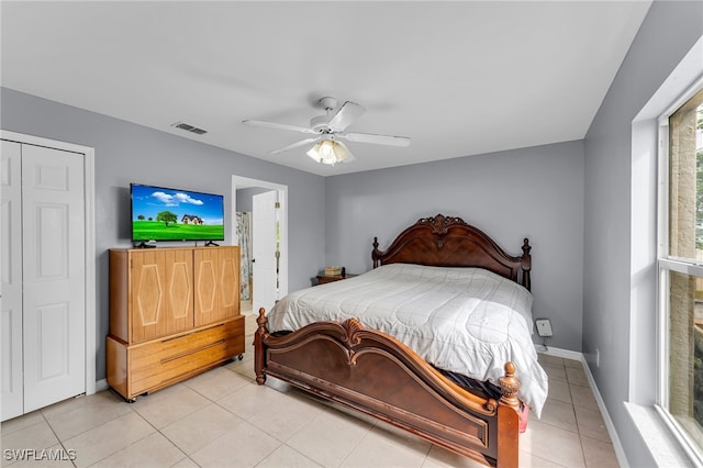 tiled bedroom featuring ceiling fan, a closet, and ensuite bath