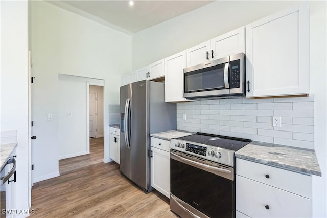 kitchen featuring light hardwood / wood-style floors, light stone countertops, white cabinetry, and stainless steel appliances