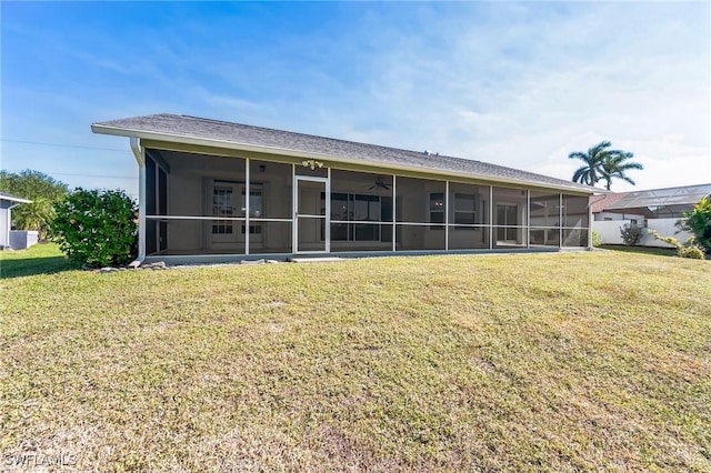 rear view of house featuring a lawn and a sunroom