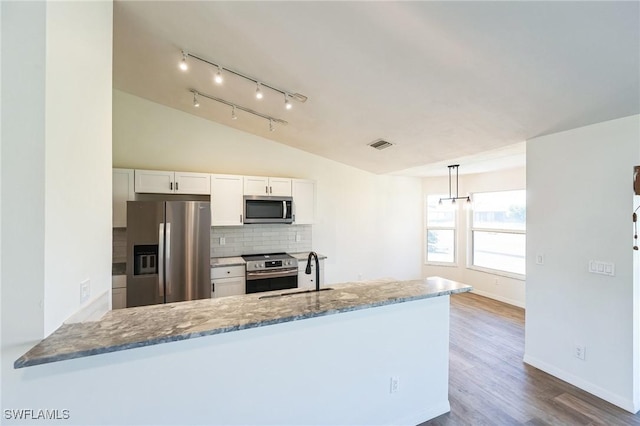 kitchen with stainless steel appliances, sink, hardwood / wood-style flooring, white cabinetry, and lofted ceiling