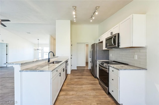 kitchen with white cabinets, appliances with stainless steel finishes, kitchen peninsula, and sink