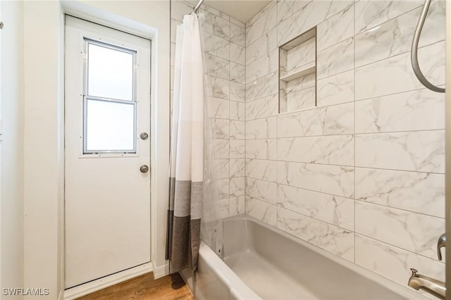 bathroom with hardwood / wood-style flooring and shower / bath combo with shower curtain