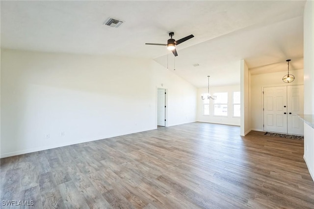 unfurnished living room featuring ceiling fan with notable chandelier, lofted ceiling, and hardwood / wood-style flooring