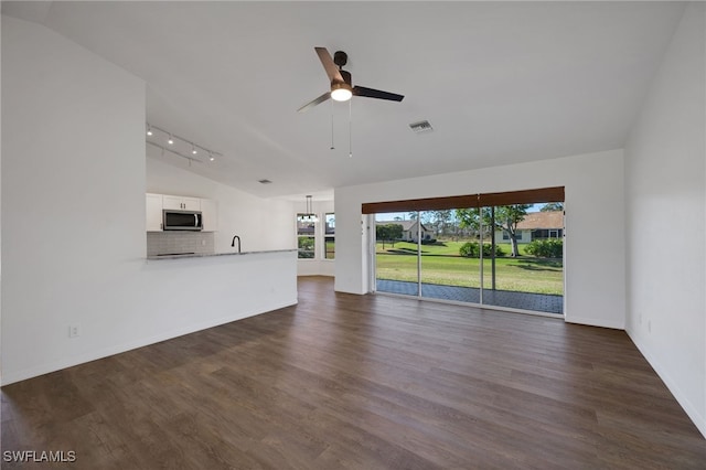 unfurnished living room with dark hardwood / wood-style flooring, rail lighting, ceiling fan, sink, and lofted ceiling